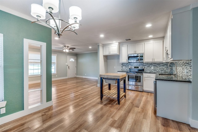 kitchen featuring ceiling fan with notable chandelier, sink, decorative light fixtures, white cabinetry, and stainless steel appliances