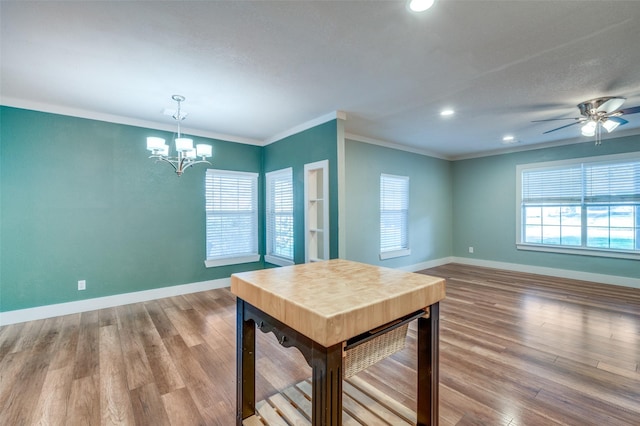 dining space featuring ceiling fan with notable chandelier, hardwood / wood-style flooring, and crown molding