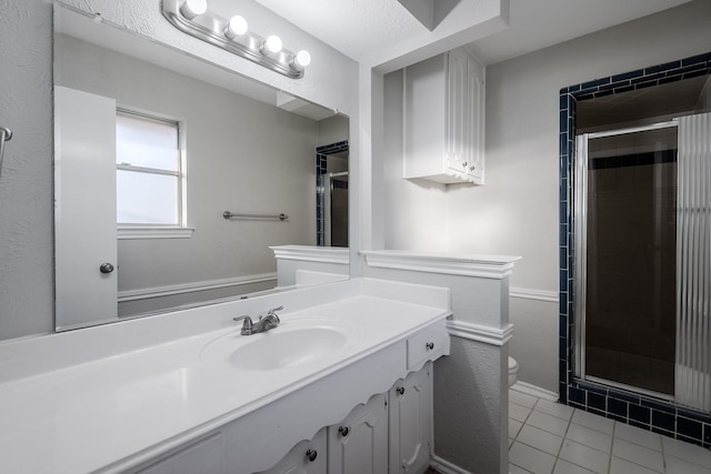 bathroom with tile patterned floors, a shower with door, vanity, and toilet