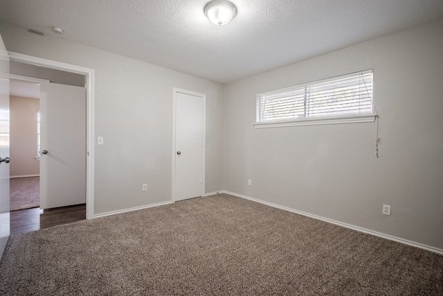 unfurnished room featuring dark colored carpet and a textured ceiling