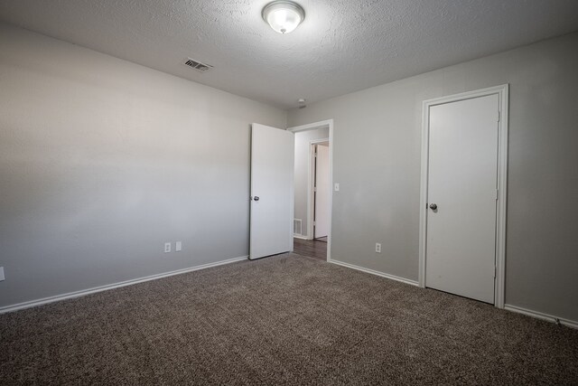 unfurnished bedroom featuring dark carpet and a textured ceiling