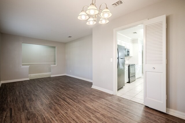 empty room with a notable chandelier and light hardwood / wood-style floors