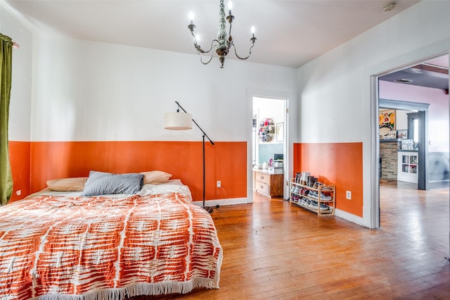 bedroom with hardwood / wood-style floors and an inviting chandelier