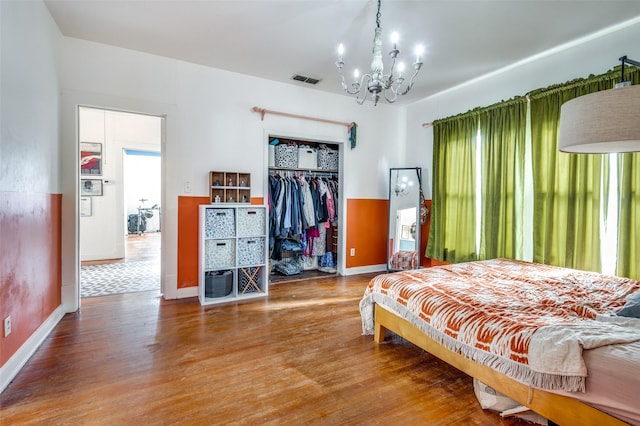 bedroom featuring hardwood / wood-style flooring, a chandelier, multiple windows, and a closet