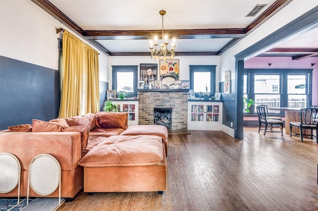 living room featuring a brick fireplace, plenty of natural light, wood-type flooring, and a notable chandelier