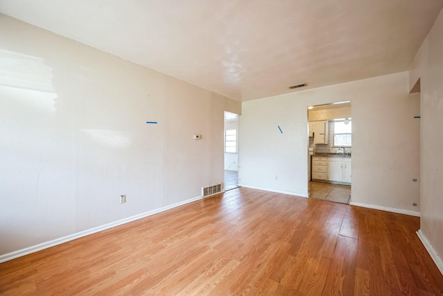 spare room featuring plenty of natural light, sink, and light hardwood / wood-style flooring