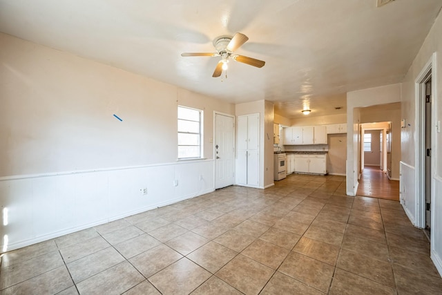 unfurnished living room featuring ceiling fan and light tile patterned floors