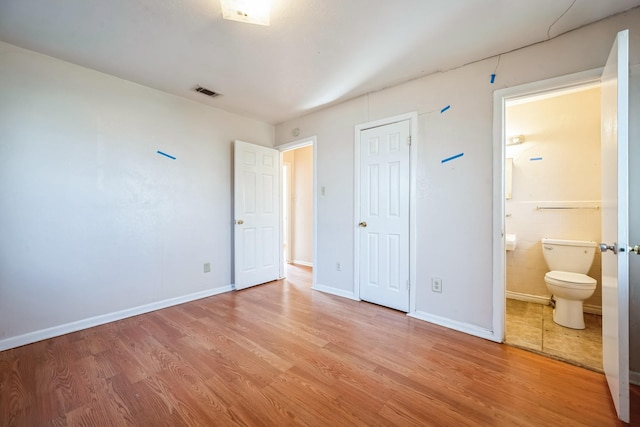 unfurnished bedroom with connected bathroom, a closet, and light wood-type flooring