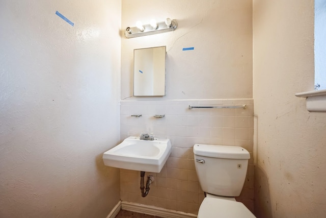 bathroom featuring sink, tile walls, and toilet