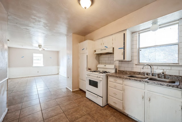 kitchen featuring ceiling fan, sink, decorative backsplash, white cabinets, and white gas range oven