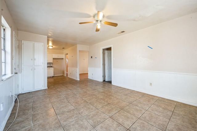 empty room with ceiling fan and light tile patterned floors