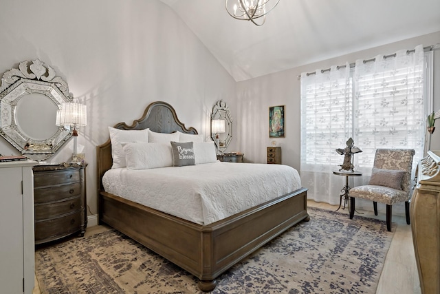 bedroom featuring light hardwood / wood-style floors, vaulted ceiling, and a notable chandelier