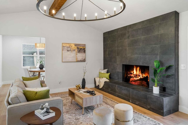 living area with lofted ceiling, baseboards, wood finished floors, and a tile fireplace