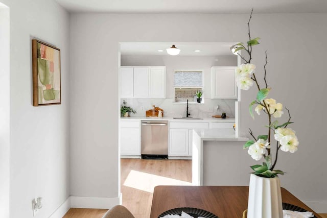 kitchen with a sink, white cabinetry, light countertops, and dishwasher