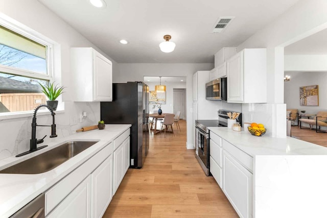 kitchen featuring white cabinetry, appliances with stainless steel finishes, light countertops, and a sink