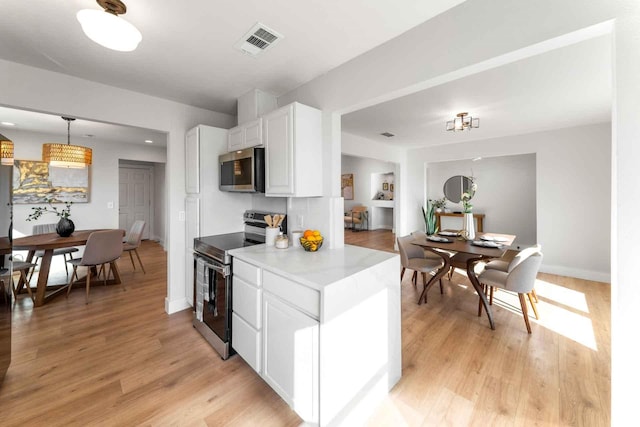 kitchen featuring visible vents, appliances with stainless steel finishes, light countertops, white cabinetry, and pendant lighting