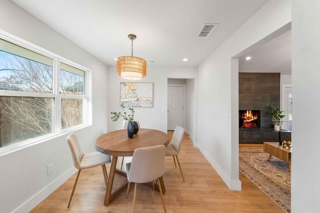 dining room featuring baseboards, visible vents, a tiled fireplace, light wood-type flooring, and recessed lighting