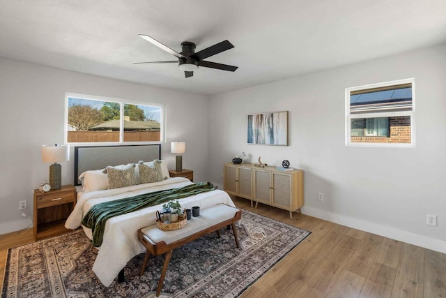 bedroom with ceiling fan, wood finished floors, and baseboards