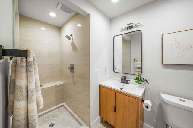 bathroom featuring visible vents, toilet, a tile shower, vanity, and recessed lighting