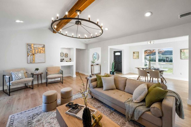 living room with vaulted ceiling with beams, a notable chandelier, and light hardwood / wood-style floors