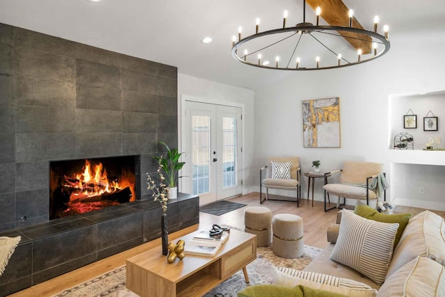 living area with a fireplace, baseboards, wood finished floors, and french doors