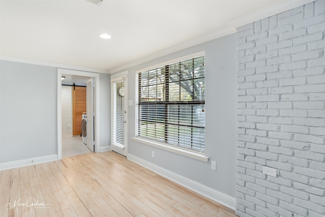 empty room featuring a barn door, ornamental molding, and light hardwood / wood-style flooring