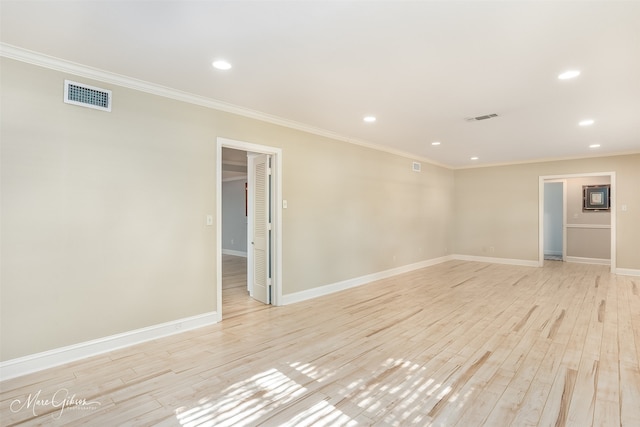 spare room featuring ornamental molding and light wood-type flooring