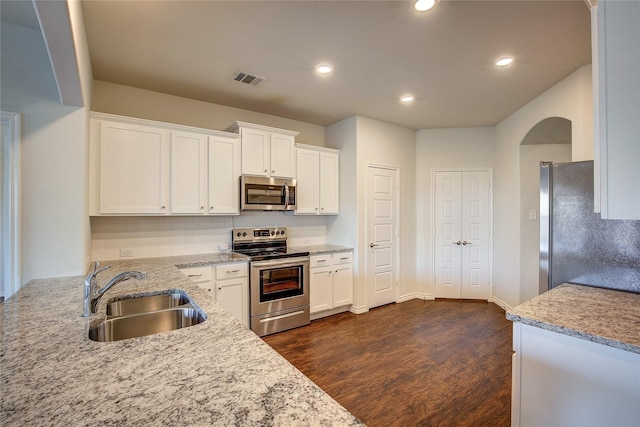 kitchen with appliances with stainless steel finishes, light stone counters, white cabinetry, and sink