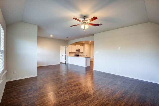 unfurnished living room with a healthy amount of sunlight, vaulted ceiling, ceiling fan, and dark wood-type flooring