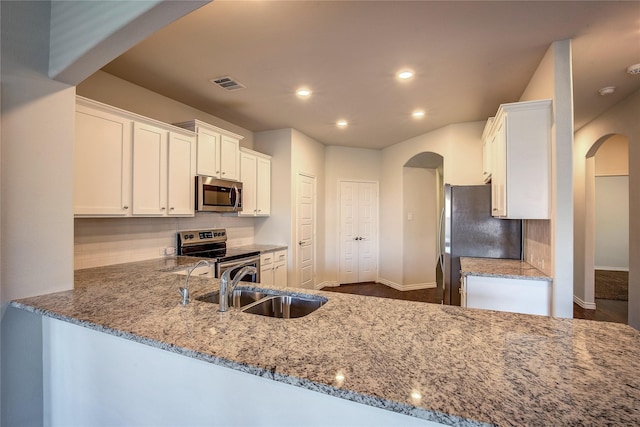 kitchen featuring kitchen peninsula, light stone countertops, white cabinets, and appliances with stainless steel finishes