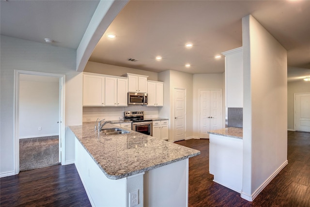 kitchen featuring light stone countertops, white cabinetry, sink, stainless steel appliances, and kitchen peninsula