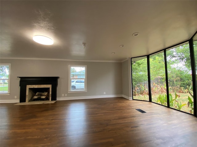 unfurnished living room with a tiled fireplace, a healthy amount of sunlight, dark hardwood / wood-style floors, and ornamental molding