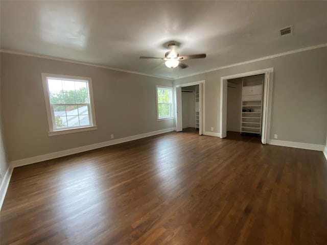 unfurnished bedroom with multiple windows, dark wood-type flooring, ceiling fan, and crown molding