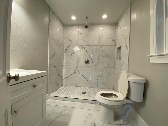 bathroom with a tile shower, vanity, and toilet