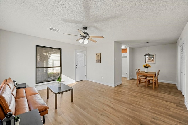 living room featuring ceiling fan, a textured ceiling, and light hardwood / wood-style flooring