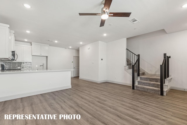 unfurnished living room with sink, ceiling fan, and light wood-type flooring