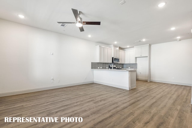 kitchen with kitchen peninsula, stainless steel appliances, ceiling fan, light hardwood / wood-style flooring, and white cabinets