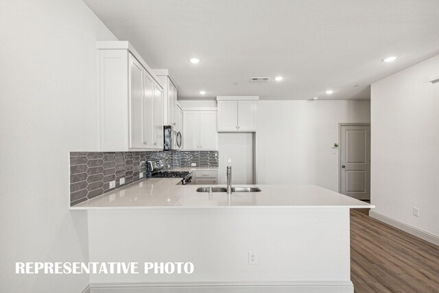 kitchen featuring kitchen peninsula, range, white cabinets, and sink