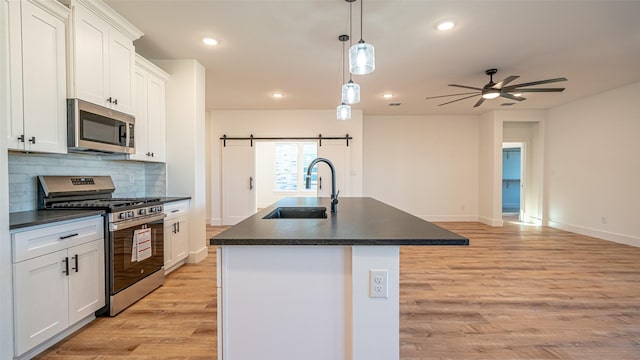 kitchen with white cabinetry, a kitchen island with sink, sink, and stainless steel appliances