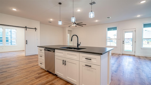 kitchen featuring light wood-type flooring, white cabinets, a kitchen island with sink, sink, and dishwasher