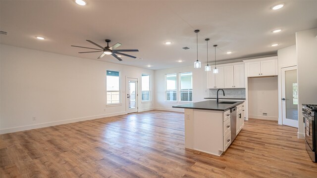 kitchen with a center island with sink, white cabinets, pendant lighting, and light hardwood / wood-style flooring