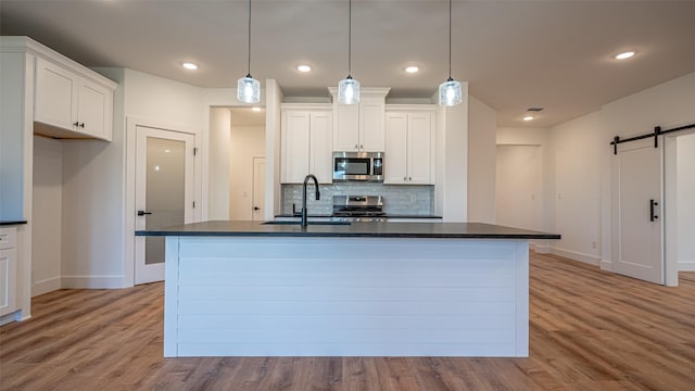 kitchen featuring white cabinets, a barn door, sink, and appliances with stainless steel finishes