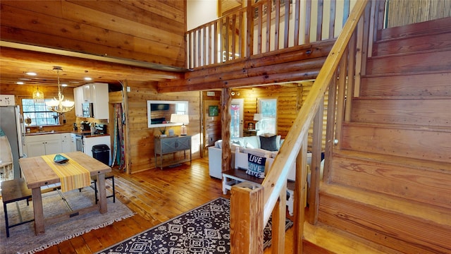 dining area featuring rustic walls, sink, a notable chandelier, a high ceiling, and light hardwood / wood-style floors