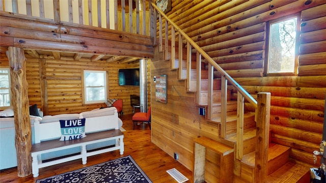 stairway with log walls and hardwood / wood-style flooring