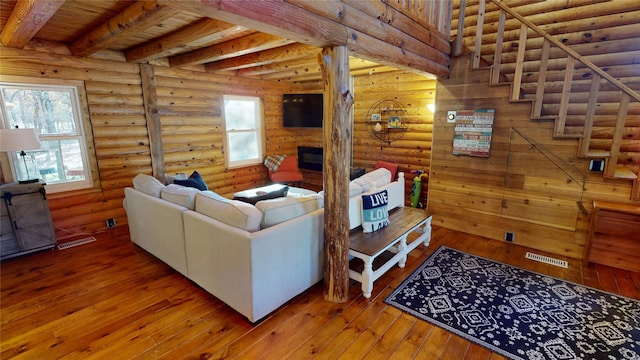 living room with beamed ceiling, hardwood / wood-style flooring, rustic walls, and wood ceiling