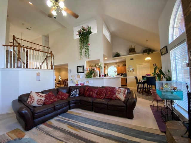 living room featuring carpet flooring, ceiling fan, and a towering ceiling