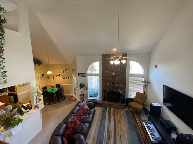 carpeted living room featuring ceiling fan, a fireplace, and high vaulted ceiling