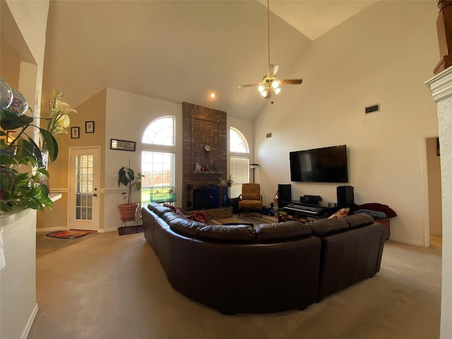 carpeted living room with ceiling fan, a large fireplace, and high vaulted ceiling