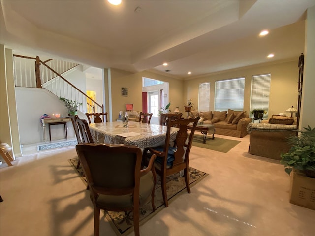 carpeted dining space with ornamental molding and a raised ceiling