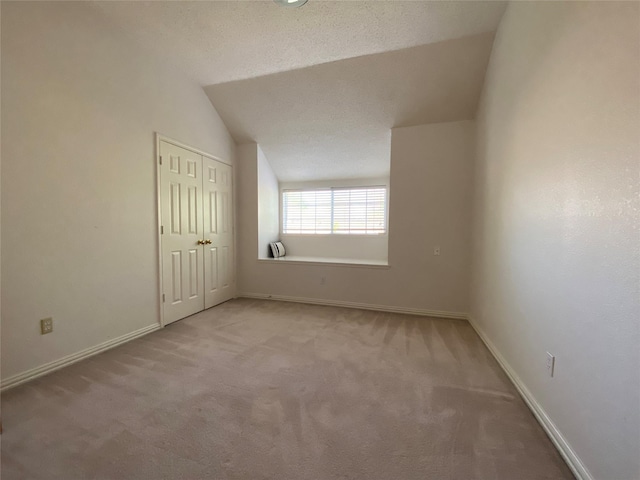 carpeted spare room featuring a textured ceiling and vaulted ceiling